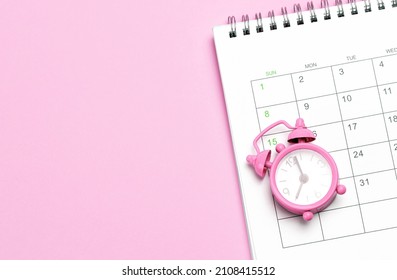 Pink alarm clock and calendar on a pink background. Concept days of menstruation or menopause. Template Copy space for text. mock-up. - Shutterstock ID 2108415512