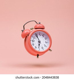 The pink alarm clock is levitate in the air, against pink background. The concept of time, copy space. - Shutterstock ID 2048443838