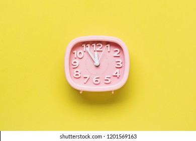 Pink alarm clock lying on yellow surface background. Top view.  - Shutterstock ID 1201569163