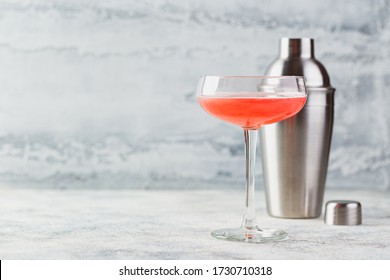 Pink alcoholic cocktail with lemonade, champagne or Martini in a champagne glass and shaker on light, cocktail like Daiquiri, Cosmopolitan, Pink Mimosa or Margarita. Summer refreshment drinks.