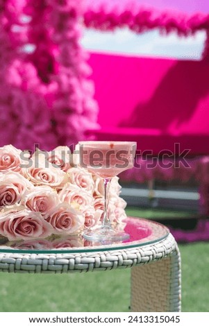 Pink alcoholic cocktail on a table with roses on the background of a pink terrace. Barbie concept