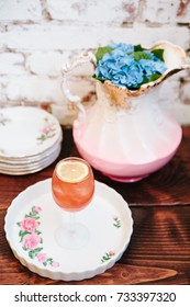 Pink Alcoholic Coktail In A Tall Wine Glass Next To Vintage Tableware