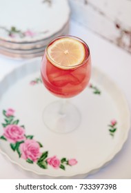 Pink Alcoholic Coktail In A Tall Wine Glass Next To Vintage Tableware