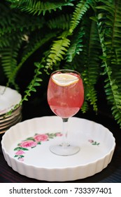 Pink Alcoholic Coktail In A Tall Wine Glass Next To Vintage Tableware