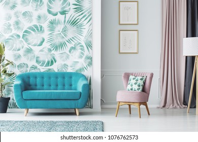 Pink Armchair Next To Blue Sofa In Living Room Interior With Posters And Green Wallpaper