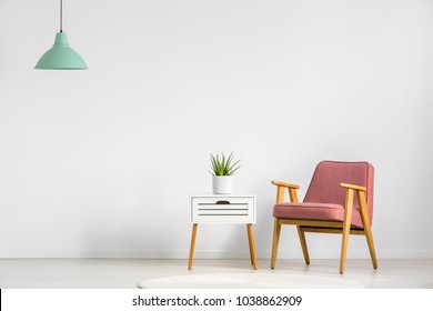 Pink Armchair And Wooden Table On Empty Wall In Simple Living Room Interior