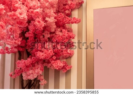Lot of pink artificial flowers on a striped painted wall