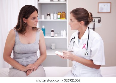 Pink awareness ribbon against doctor taking notes