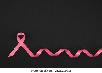 A pink awareness ribbon placed on a black surface highlights cancer awareness initiatives. - Powered by Shutterstock