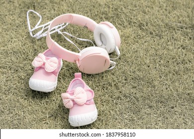 Pink Baby Girl's Shoes And Headphone Put On Grass With Copy Space. New Born, Mother Love, Charity And Growth Concept.