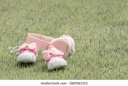 Pink Baby Girl's Shoes And Headphone Put On Grass With Copy Space. New Born, Mother Love, Charity And Growth Concept.