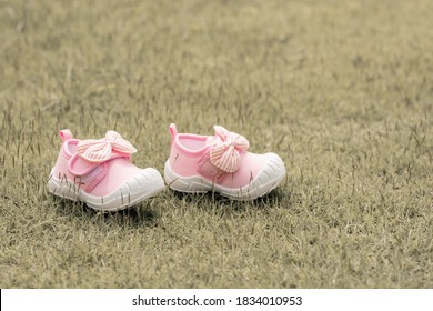 Pink Baby Girl's Shoes Put On Grass With Copy Space. New Born, Mother Love, Charity And Growth Concept.