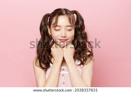 Pink background portrait of a young Asian woman with pigtails