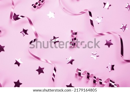 Pink background with a silver serpentine and stars. concept of celebrating a birthday,newborn , party or anniversary in silver tones