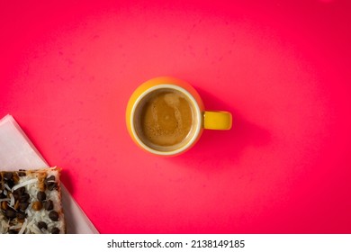 Pink Backgrounds With A Mug Of Espresso Coffee In The Middle. Cake Slice Decorated With Coconut Chips And Chocolate Chip Sneaking From The Corner