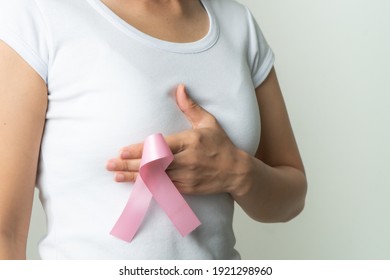 pink badge ribbon on woman hand touching chest to support breast cancer cause. breast cancer awareness concept - Shutterstock ID 1921298960