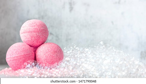 Pink bath balls on a background of soapy foam. Banner or background, copy space.