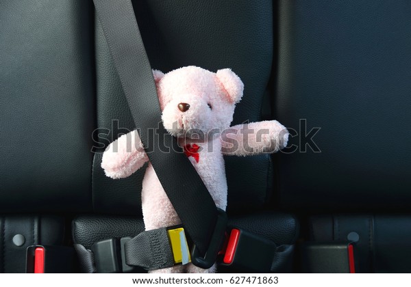 Pink bear on back seat car with safety belt in\
safety travel on the road