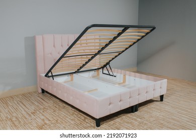 A Pink Bed With A Storage Space Revealed By Lifting The Wooden Slatted Base