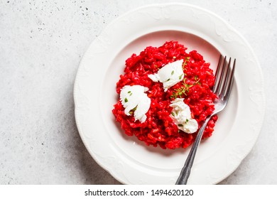 Pink beetroot risotto with feta cheese in a white plate.