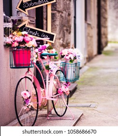 Pink bicycle with inspirational quotes on a billboard parked in a small Mediterranean alley. Life meaning and opportunities. Journey destinations and vacation plans. People in love enjoying life.