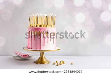 Pink birthday cake decorated with gold drip icing, gold leaf and lots of gold birthday candles