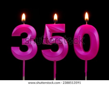 Pink birthday candles burning on black background, number 350.   