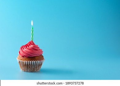 Pink Birthday Cupcake With Green Candle On Blue Background