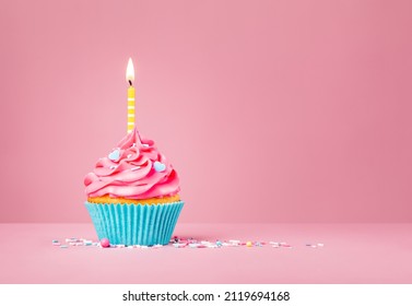 Pink Birthday Cupcake With Yellow Candle And Blue Heart Sprinkles