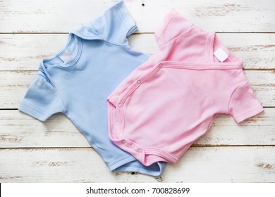 Pink And Blue Baby Romper On White Wooden Background
