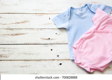 Pink And Blue Baby Romper On White Wooden Background. Copysp
