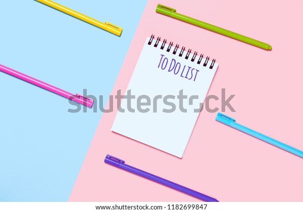 Pink and blue background with colorful pens.\
Minimalist stationary concept. To Do list notebook. Empty notebook.\
Flat lay top view. Study arrangement, making wish list or plans.\
Minimalist style