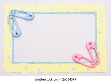 Pink and blue diaper pins sitting on a yellow alphabet background, baby border