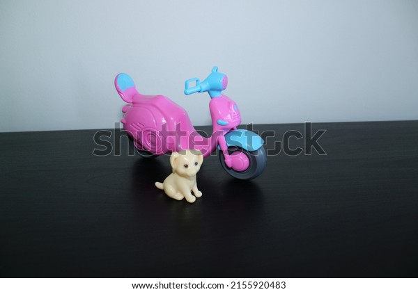 Pink and blue plastic toy motorbike with a cute\
plastic toy dog in the\
front
