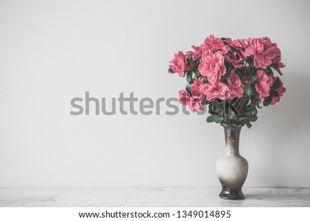 Pink bouquet of azalea in clay vase on table at gray wall. Empty place for inspirational, emotional, sentimental text, quote or sayings. Front view.