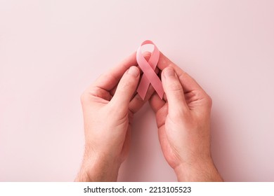 Pink Breast Cancer Awareness Ribbon. Hands Holding Red Gerbera And Pink Ribbon On Backgrounds. Breast Cancer Awareness And October Pink Day, World Cancer Day. Top View. Mock Up.