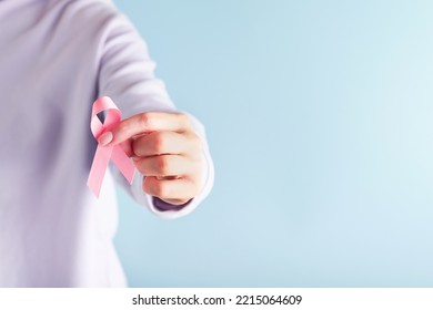 Pink Breast Cancer Awareness Ribbon. Female hands holding pink ribbon on blue backgrounds. Breast cancer awareness and October Pink day, world cancer day. Top view. Mock up. - Powered by Shutterstock