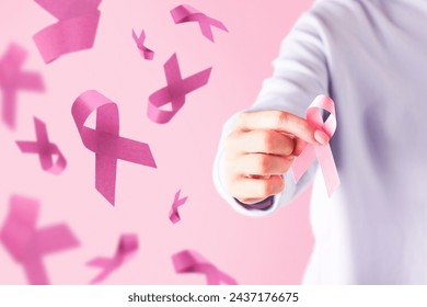 Pink Breast Cancer Awareness Ribbon. Female hand holding pink ribbon flying symbol of fight against breast cancer. Breast cancer awareness and October Pink day, world cancer day. Top view. Mock up. - Powered by Shutterstock