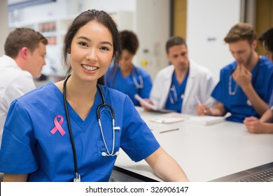 Pink breast cancer awareness ribbon against medical student smiling at the camera during class