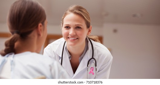 Pink breast cancer awareness ribbon against smiling doctor looking at a patient on a wheelchair
