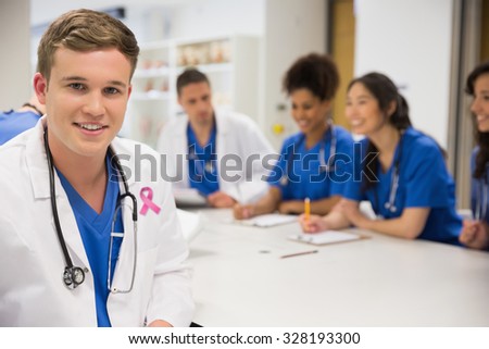 Pink breast cancer awareness ribbon against medical student smiling at the camera during class
