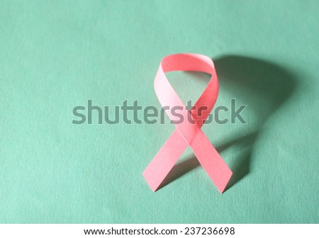 Pink breast cancer ribbon on turquoise background