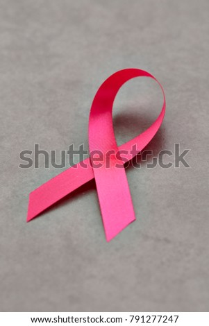 Pink breast cancer ribbon on gray background, minimal concept