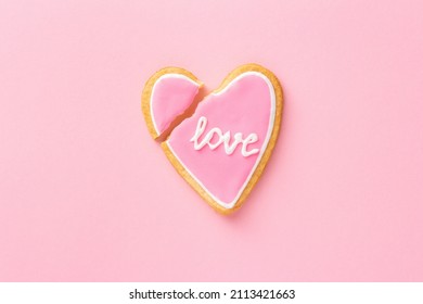 Pink broken cookie heart with word LOVE, top view, flat lay. Breakup or divorce concept.