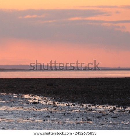 Pink sky’s and calm sea at Minster-on-sea on the Isle of Sheppey, Kent. Flat landscape in the background is Medway and the Isle of Grain. Beautiful abstract like background.