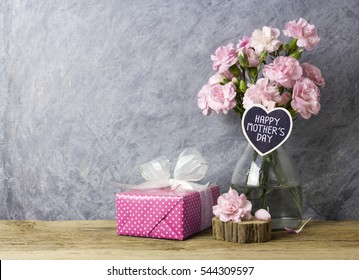 Pink carnation flowers in bottle with happy mothers day letter on heart wood and pink gift box