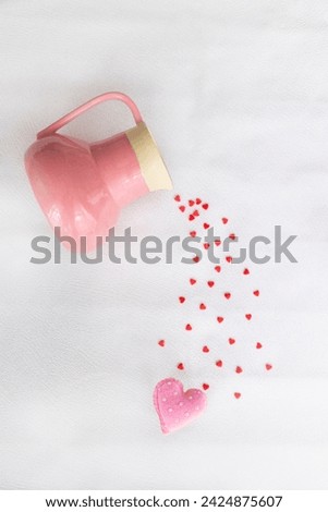 Pink ceramic jug with many tiny hearts that are pouring from it