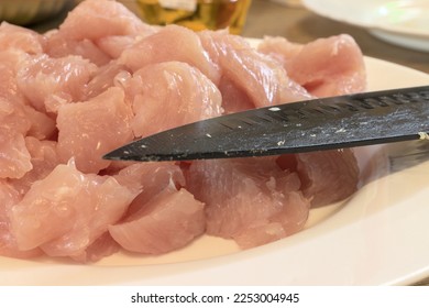 Pink chicken meat chopping with black knife during meal preparation in a wooden table in Hungary. Chicken is a healthy meat type. Homemade meal.  Chopping or portioning. Cover for cooking books - Shutterstock ID 2253004945