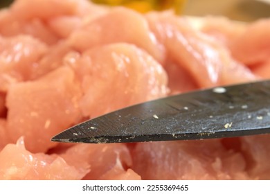 Pink chicken meat chopping with black knife during meal preparation in a wooden table in Hungary. Chicken is a healthy meat type. Homemade. Chopping or portioning. Cover for cooking books - Shutterstock ID 2255369465