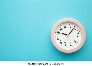 Pink clock on blue background. Top view. Space for text. Top view